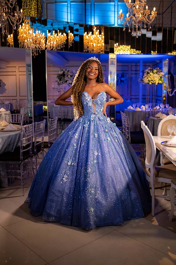 Debutante em vestido azul diante do painel iluminado em azul