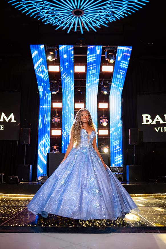 Debutante em vestido azul diante do painel de LED do salão