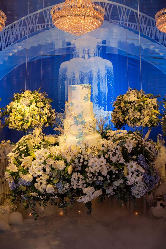 Bolo de 15 anos em branco emoldurado por arranjos de flores