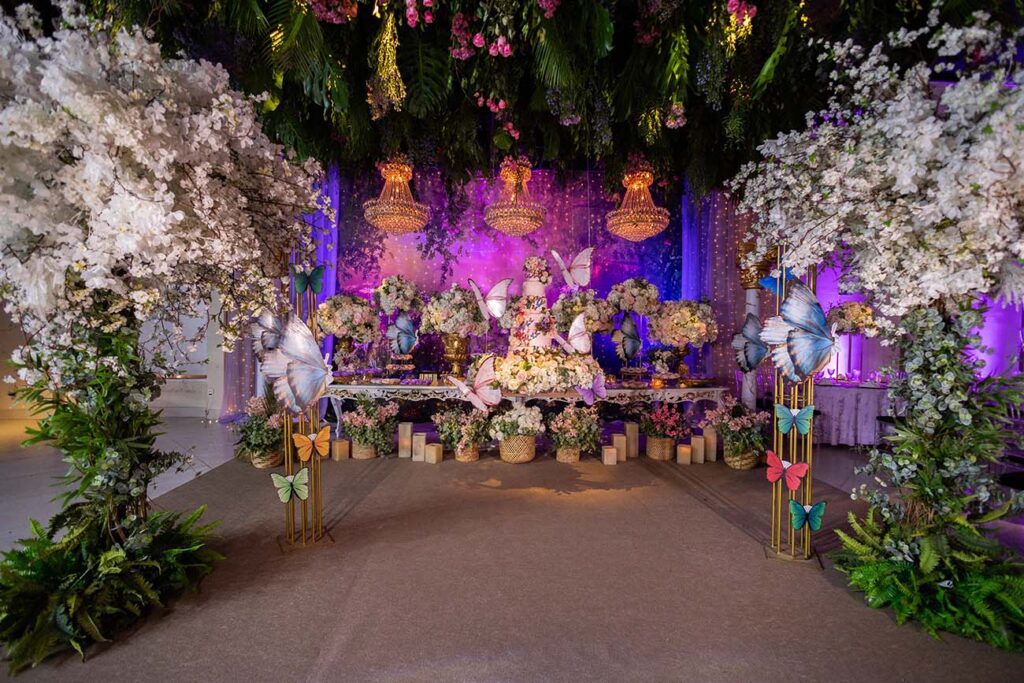 Cenário da festa com arco de flores brancas e folhagens suspensas