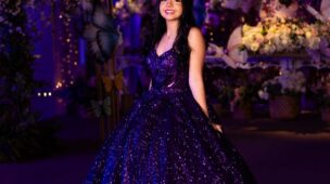Debutante em vestido roxo diante do cenário de flores e borboletas