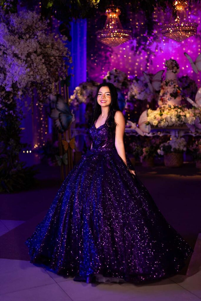 Debutante em vestido roxo diante do cenário de flores e borboletas