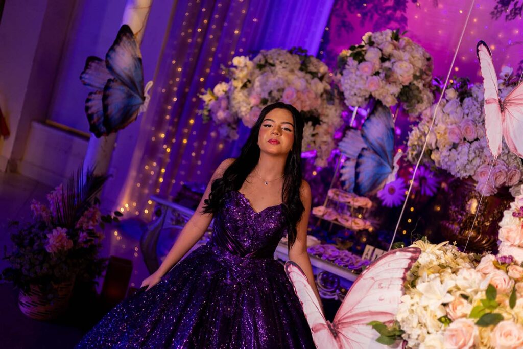 Debutante em vestido roxo entre borboletas azuis e flores
