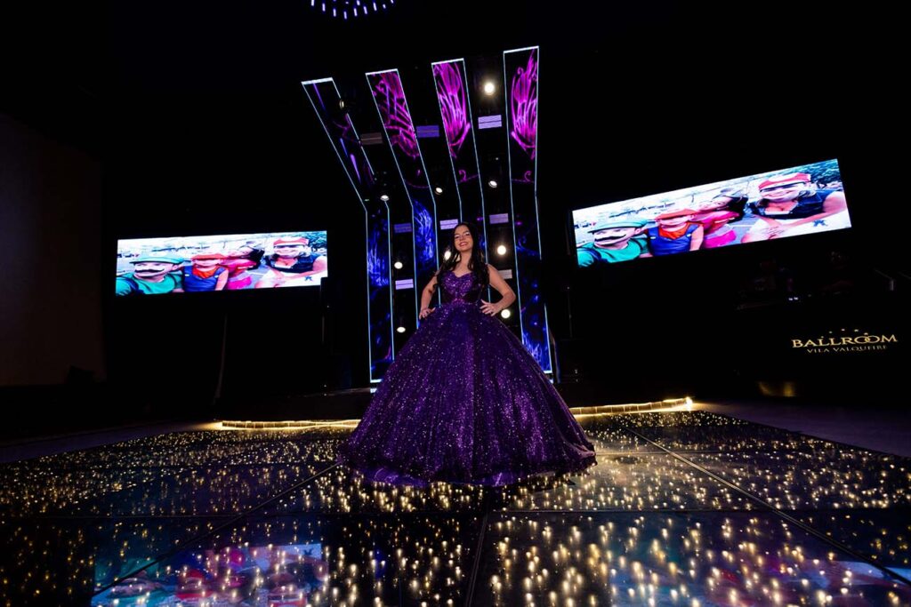 Debutante em vestido roxo na pista diante dos painéis de LED