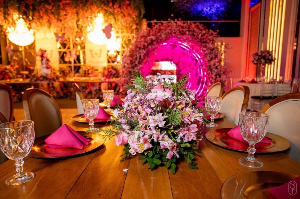 Mesa dos convidados com arranjo de flores e guardanapos pink