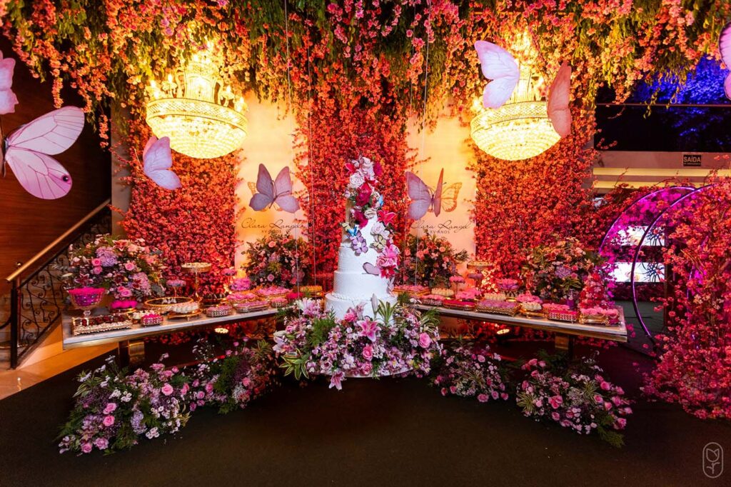 Mesa do bolo do jardim encantado com flores, borboletas e lustres de cristal