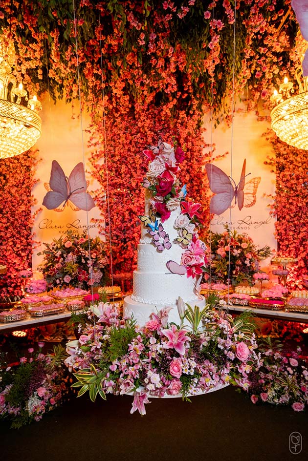 Mesa do bolo com borboletas e flores em tons de rosa