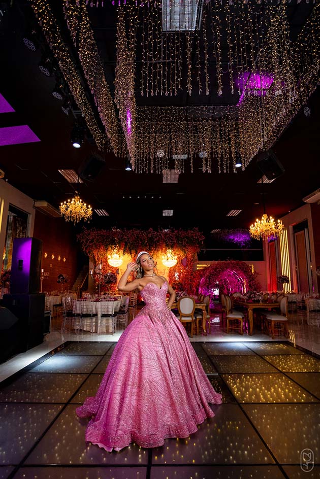 Debutante em vestido rosa na pista iluminada do salão