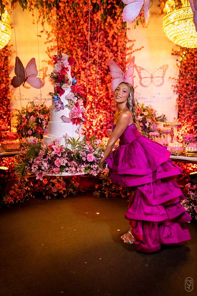 Debutante no segundo look pink diante da mesa do bolo