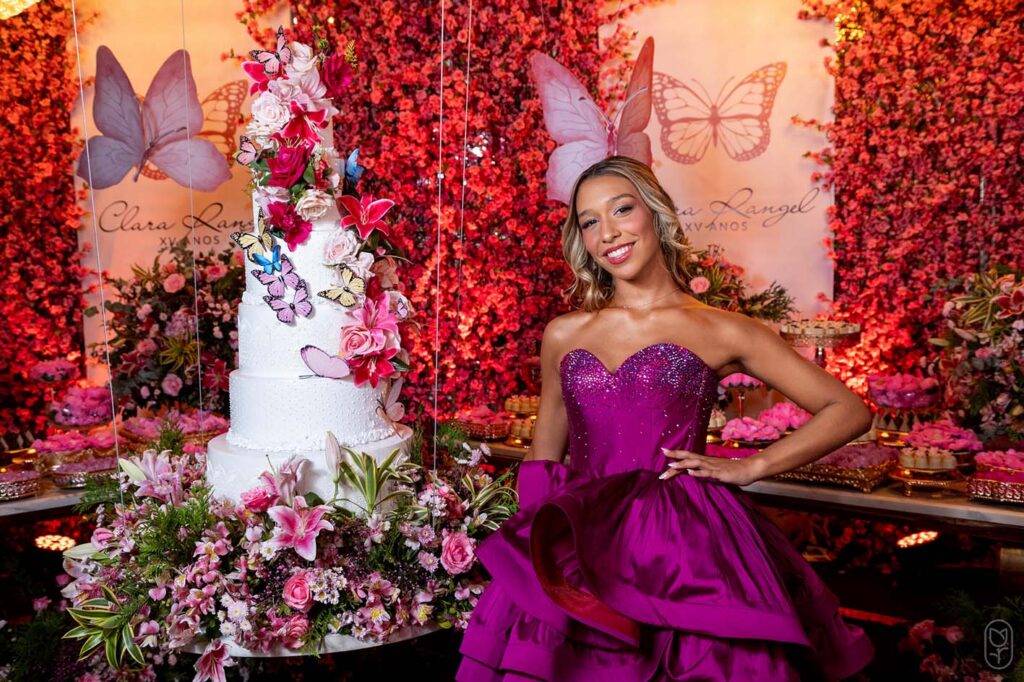 Debutante no segundo look pink ao lado da mesa do bolo