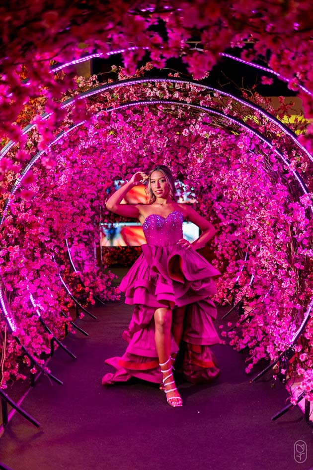 Debutante no segundo look pink diante do arco florido em rosa