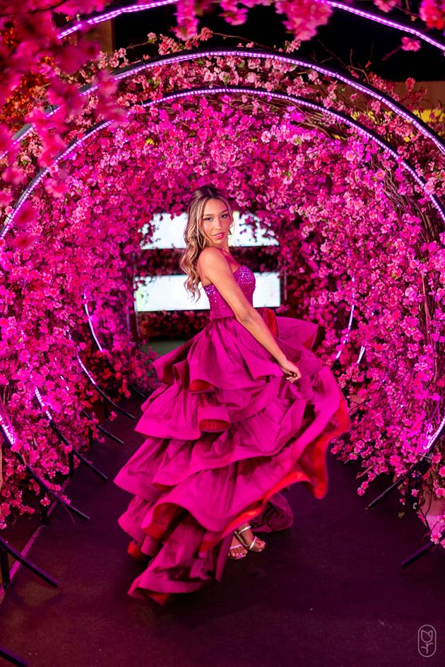 Debutante no segundo look pink sob o arco de flores iluminado