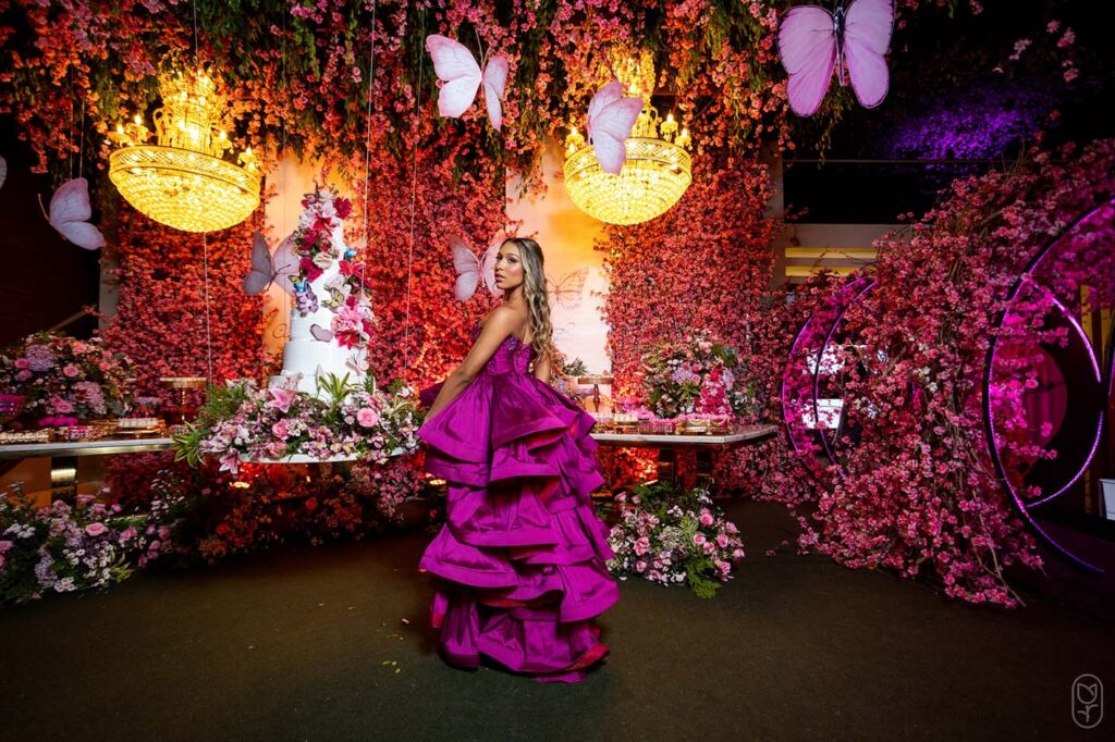 Debutante no segundo look pink diante da mesa do bolo iluminada