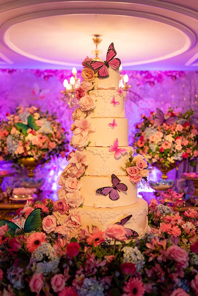 Bolo de 15 anos decorado com borboletas e cercado por flores