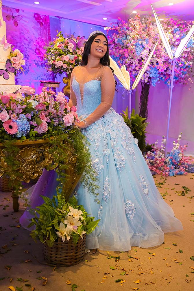 Debutante em vestido azul entre as flores do jardim encantado