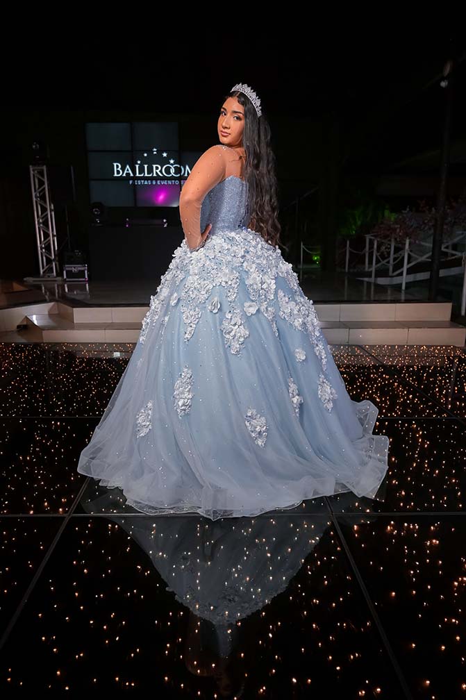 Debutante em vestido azul diante do painel escuro com luzes