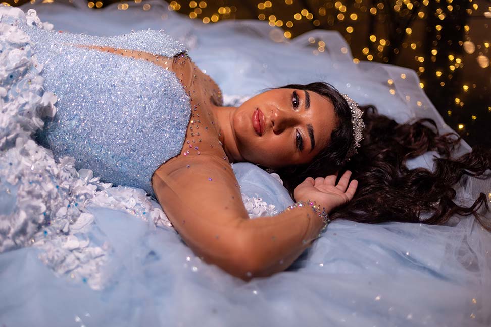 Debutante deitada com o vestido azul sob luzes douradas
