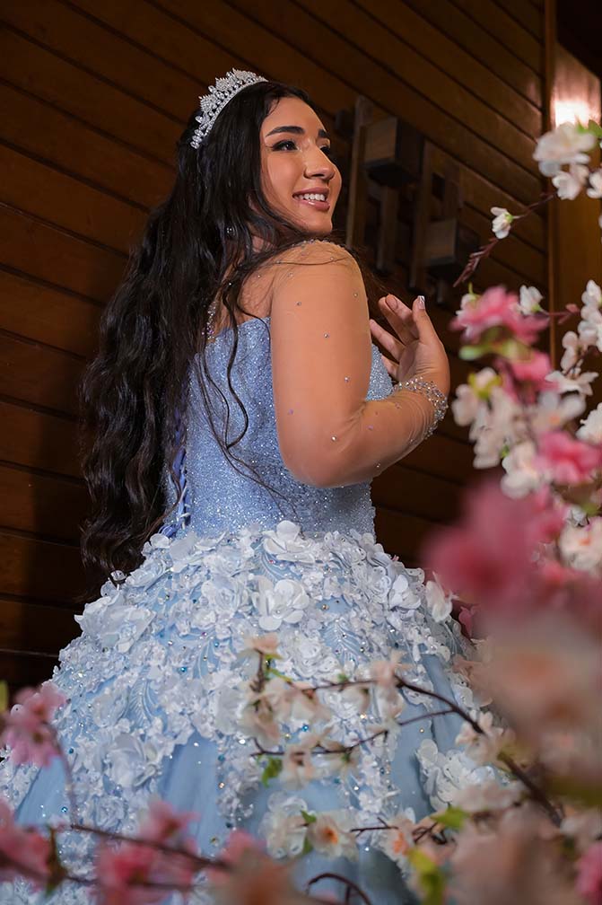 Debutante em vestido azul entre as flores da decoração