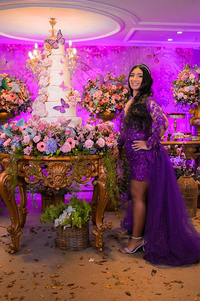 Debutante no segundo look roxo ao lado da mesa do bolo