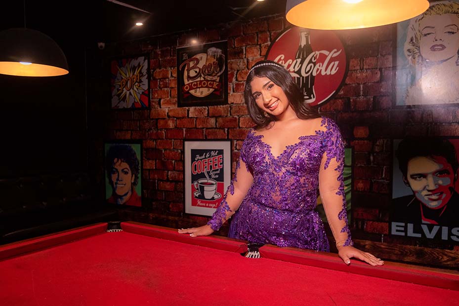 Debutante no segundo look roxo na mesa de sinuca do lounge
