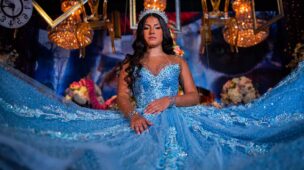 Debutante sentada com o vestido azul espalhado sob os lustres