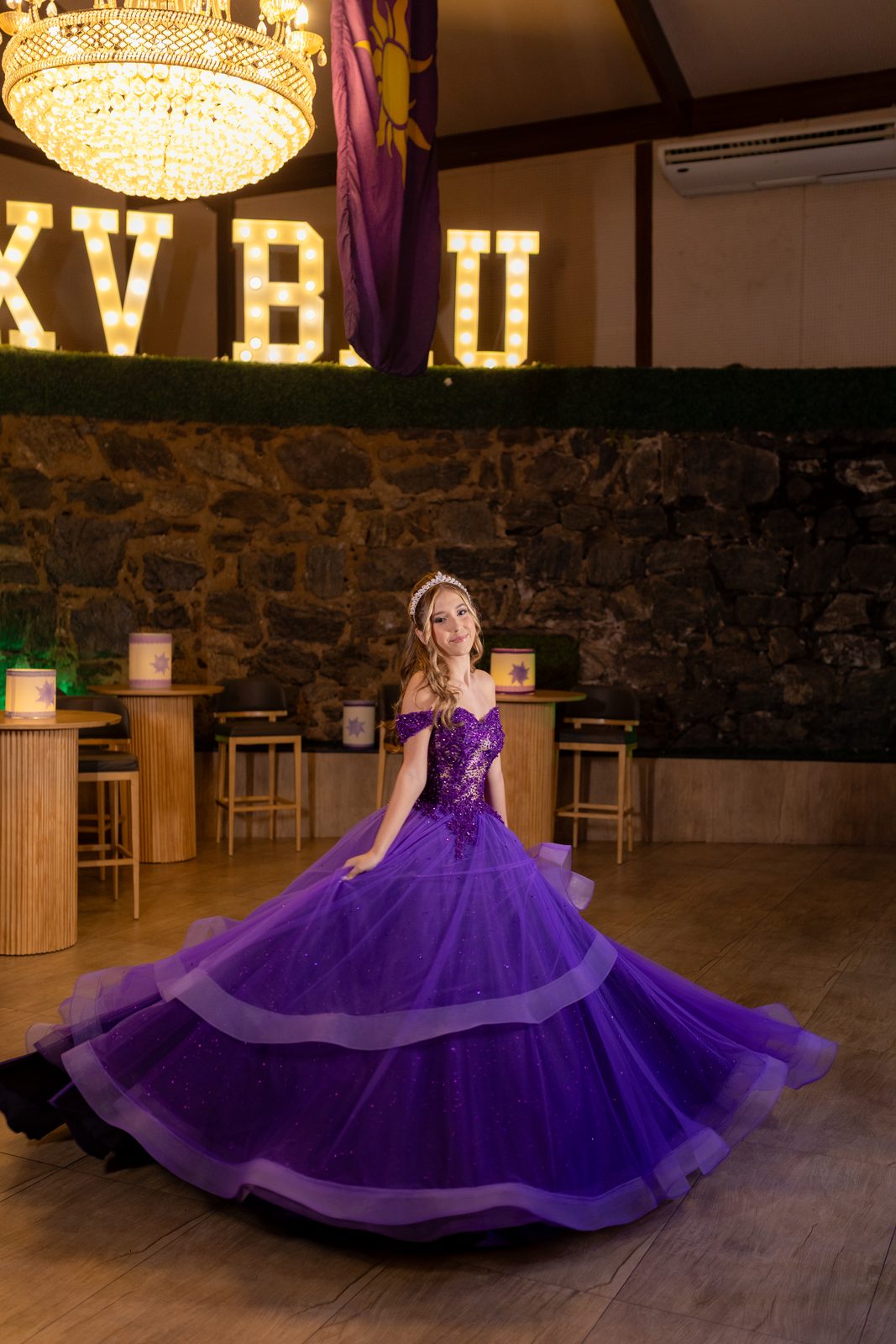 Debutante em vestido roxo de baile diante do letreiro luminoso na festa de 15 anos tema Rapunzel
