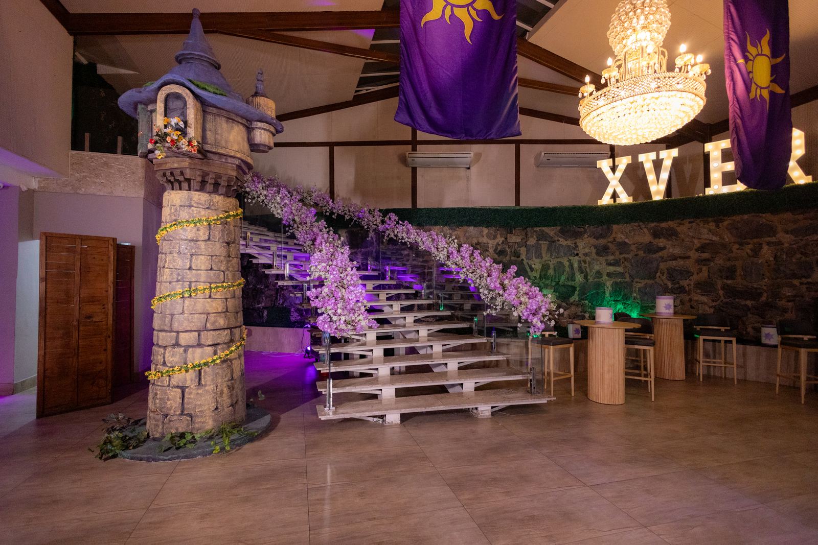Torre cenografica da Rapunzel com escadaria e cascata de flores lilas na festa de 15 anos
