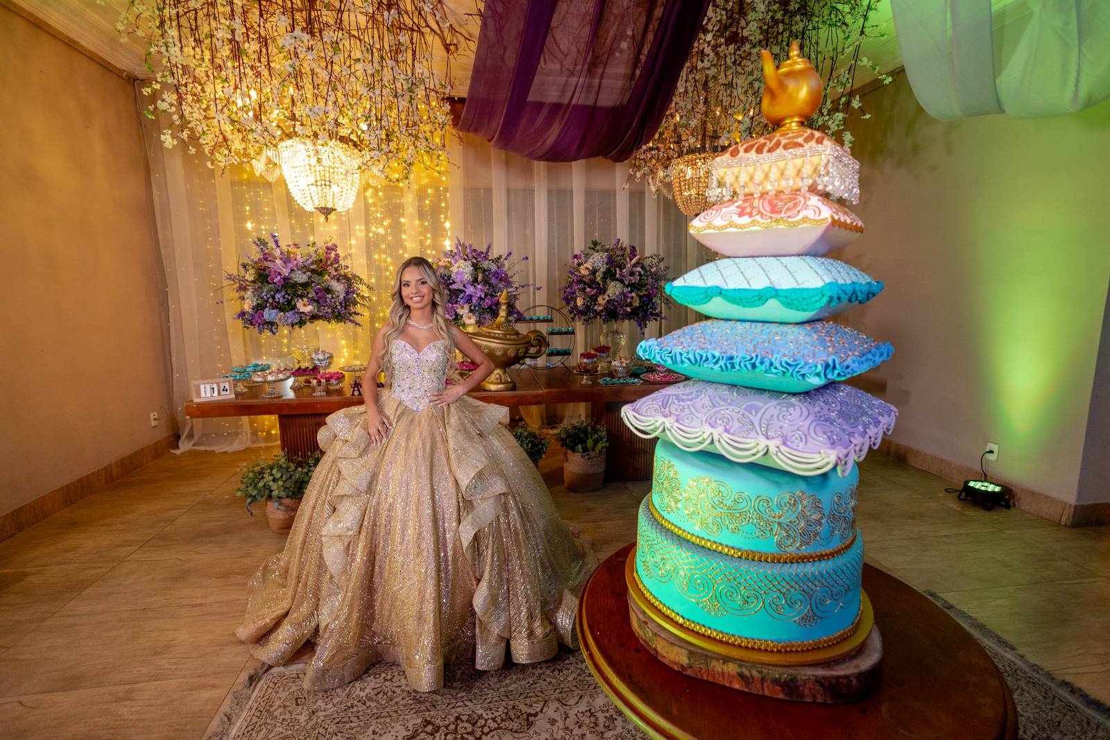 Debutante em vestido dourado ao lado do bolo tematico de Aladdin