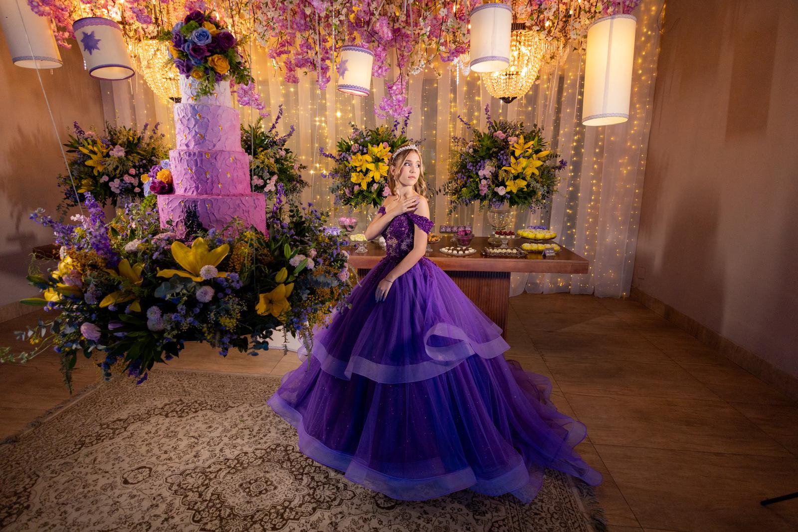 Bolo de 15 anos em lilas texturizado ao lado de arranjo em amarelo e roxo