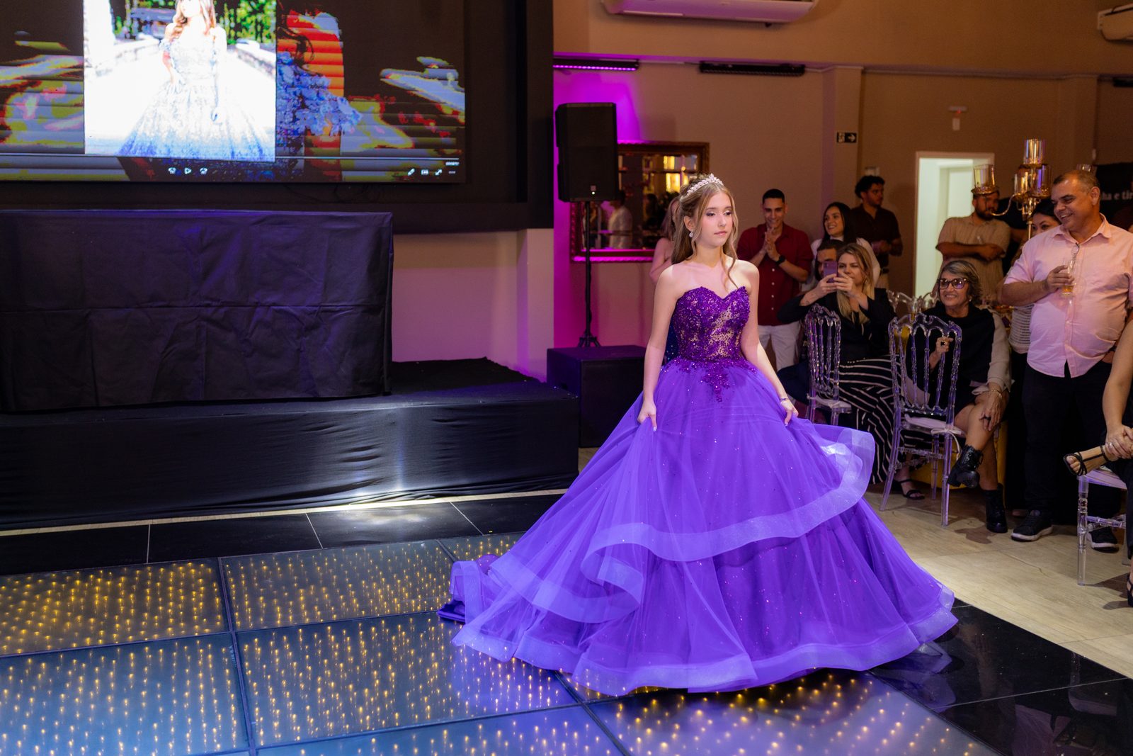 Debutante entra na pista iluminada diante dos convidados na festa de 15 anos