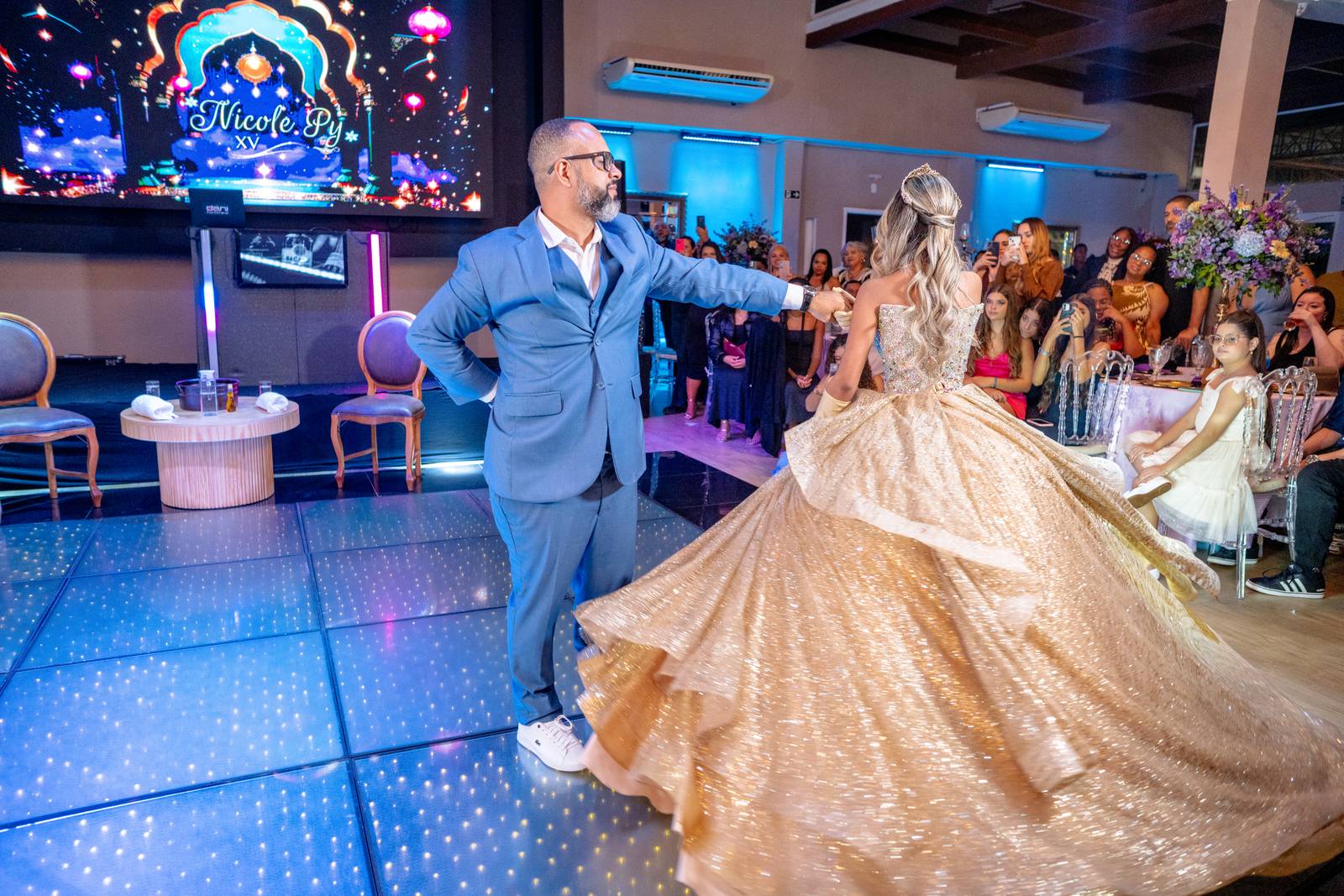 Valsa da debutante com o pai, vestido dourado em movimento na pista