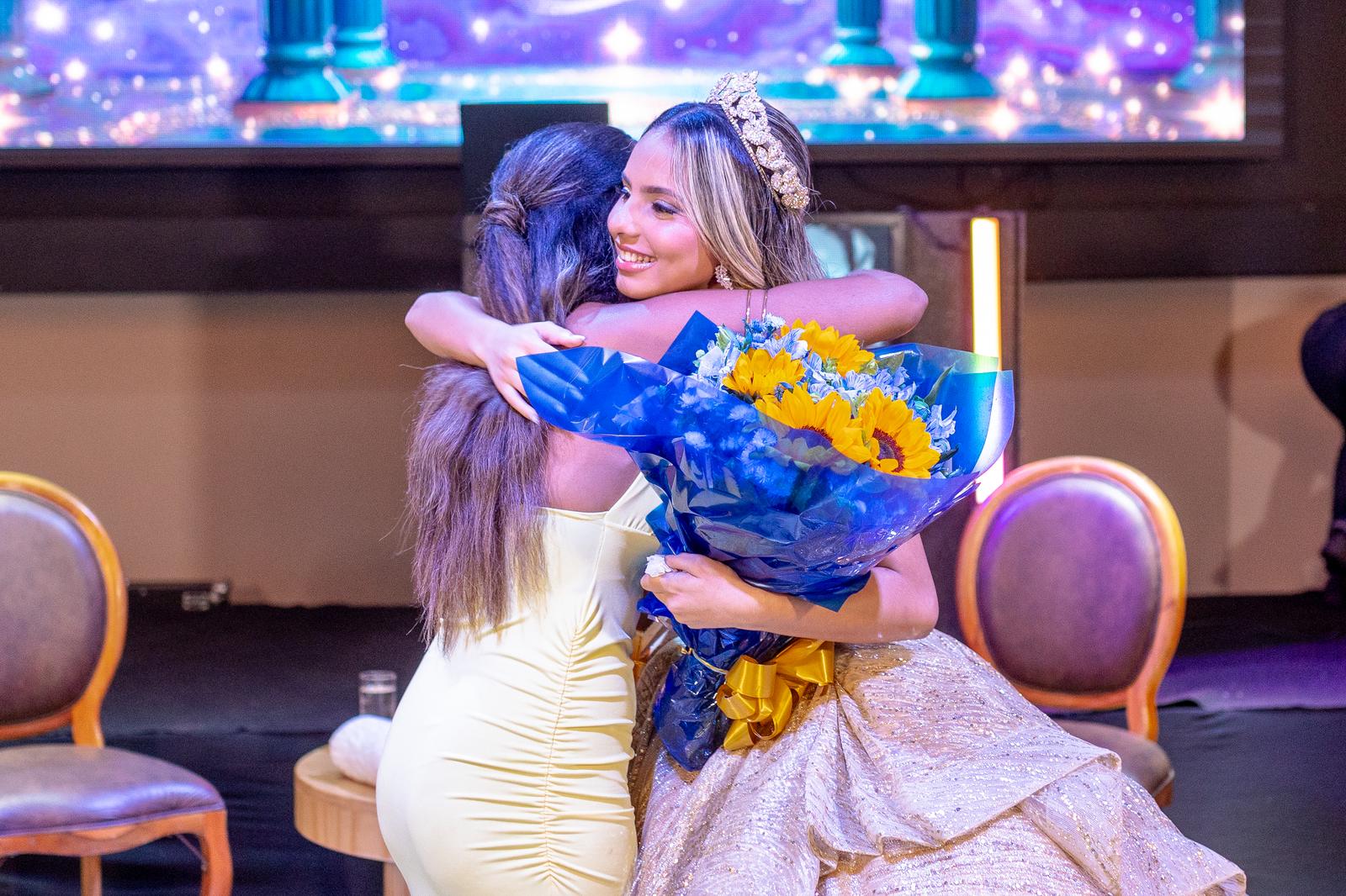 Momento de emocao da debutante recebendo buque durante a homenagem