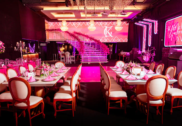 Mesas dos convidados montadas com iluminação em rosa antes da festa